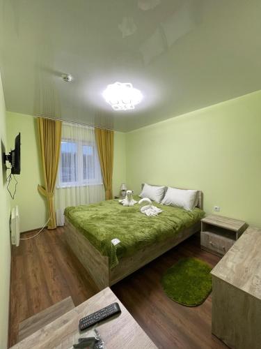 ein Schlafzimmer mit einem großen grünen Bett in einem Zimmer in der Unterkunft Готель ТІК Копичинці in Sukhostav