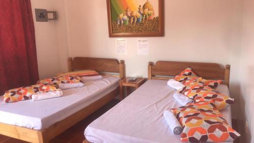 two twin beds in a room with a picture on the wall at Lotus Sun & Waves Beach Resort in Baler