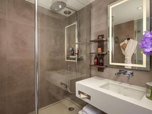 a bathroom with a shower and a sink and a mirror at Novotel Paris Les Halles in Paris