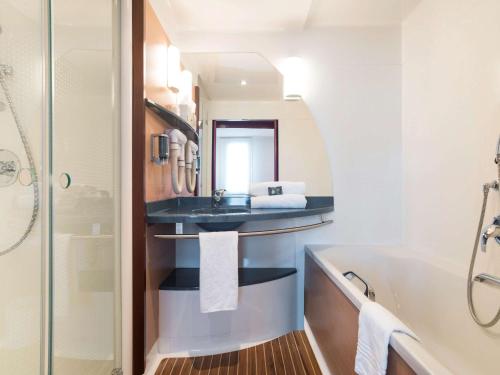 a bathroom with a sink and a tub and a mirror at Novotel Suites Reims Centre in Reims