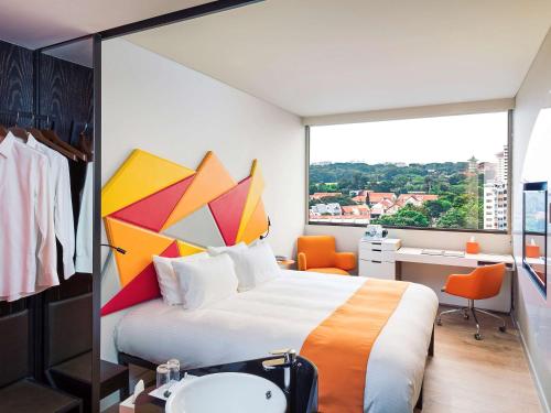 ein Hotelzimmer mit einem großen Bett und einem Waschbecken in der Unterkunft Ibis Styles Singapore On Macpherson in Singapur