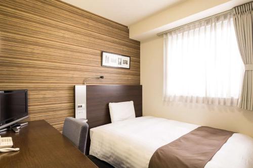 a hotel room with a bed and a desk and a television at Comfort Hotel Kumamoto Shinshigai in Kumamoto