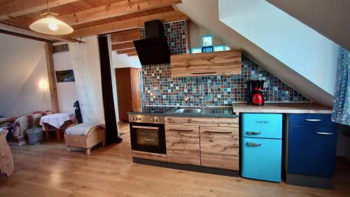 a kitchen with a stove and a blue refrigerator at Ferienappartement Rondine Bekond in Bekond