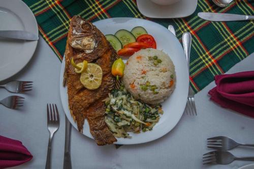a plate of food with fish and rice on a table at Panone Hotel Mererani in Mbuguni