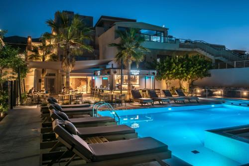 a hotel pool with lounge chairs and a resort at Riviera Boutique Hotel in Stalida