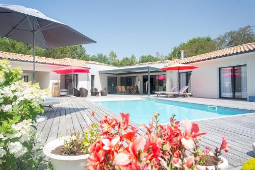 eine Villa mit einem Pool und einem Haus in der Unterkunft Dune et Coquelicot in Gaillan-en-Médoc