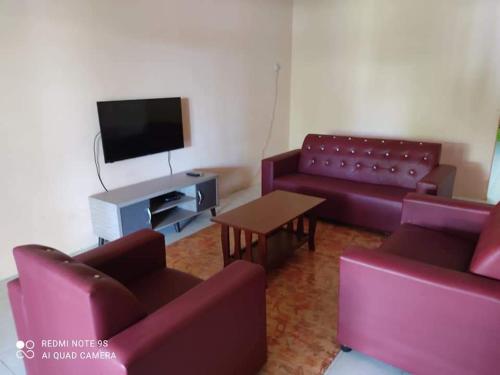 a living room with purple couches and a tv at Munir Homestay in Kampung Gurun