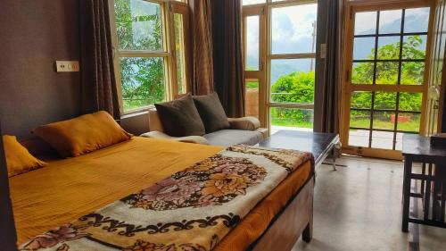 a bedroom with a bed and a couch and windows at Blue Mountain Village Cottage in Nainital