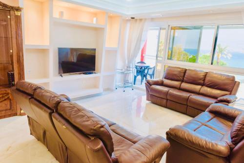 a living room with two leather couches and a television at Royal Beach Front Apartments in Netanya