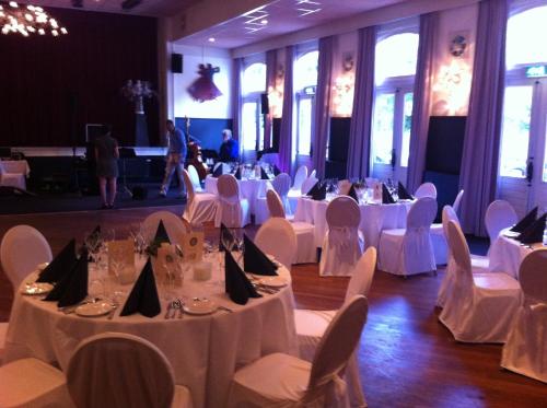 a banquet hall with white tables and white chairs at Hotel Faber in Hoogezand