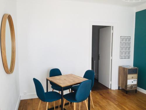 - une salle à manger avec des chaises bleues, une table et un miroir dans l'établissement Charmant T2 proche gare, avec la fibre et jardin, à Lorient