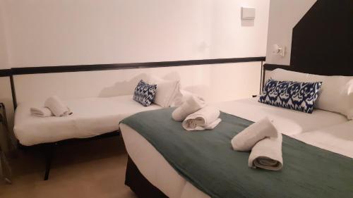 two beds in a room with towels on them at Hostal Hom Museo in Seville