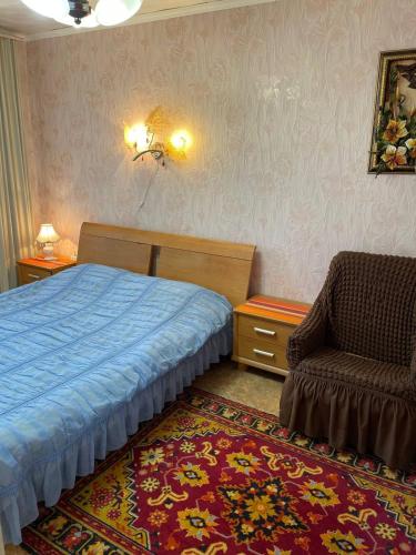 a bedroom with a bed and a chair and a rug at Солнечная двушка в порту in Kherson