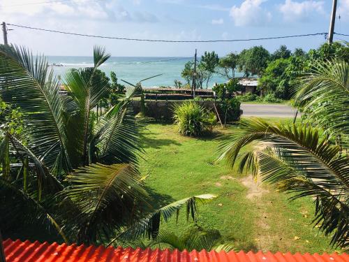a view of a yard with palm trees and the ocean at Laguna Surfing Stay in Midigama