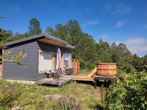 a small cabin with a bench and an umbrella and a barrel at Tiny House con Tinaja Privada en Pucón in Pucón