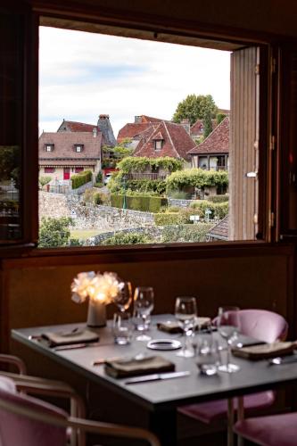 une table dans un restaurant avec une grande fenêtre dans l'établissement Hôtel le Cantou 354, à Loubressac