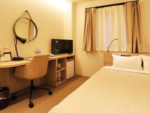 a hotel room with a bed and a desk with a computer at Odawara Terminal Hotel in Odawara