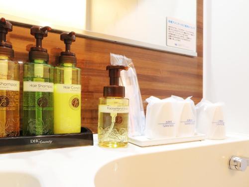 a shelf with bottles of soap and toiletries on a sink at Odawara Terminal Hotel in Odawara