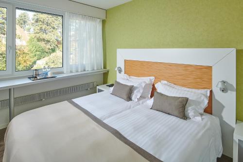 Un dormitorio con una gran cama blanca y una ventana en Le Leman Hotel, en Vevey