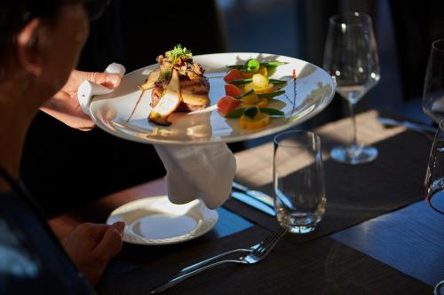 a person holding a plate of food on a table at Le Leman Hotel in Vevey