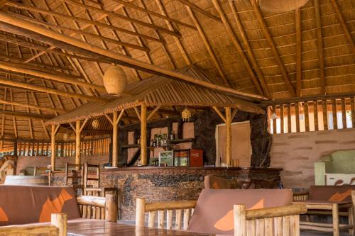 un restaurant avec un plafond en bois, des tables et des chaises dans l'établissement Tanganyika Blue Bay Resort, à Mugotora