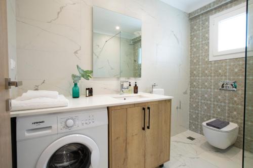 a bathroom with a washing machine and a sink at Grappolo Lefkada Villas - Villa Vertzami just 2 km from Lefkada town in Apolpaina