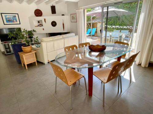 - une table et des chaises en verre dans le salon dans l'établissement Very comfortable house steps from the beach with garden and terrace, à Hourtin