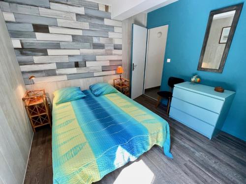 - une chambre avec un lit bleu et un mur en pierre dans l'établissement Very comfortable house steps from the beach with garden and terrace, à Hourtin