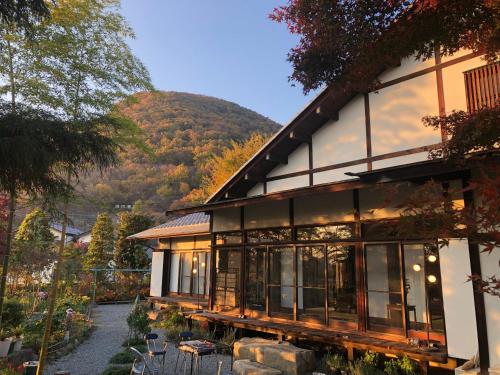 a large house with a mountain in the background at フクロウの御宿 春日居館 in Isawa