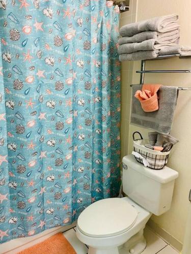 a bathroom with a toilet and a blue shower curtain at Spectacular Ocean View in Daytona Beach