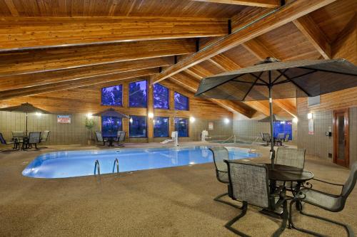 a swimming pool with a table and an umbrella at AmericInn by Wyndham Mitchell in Mitchell