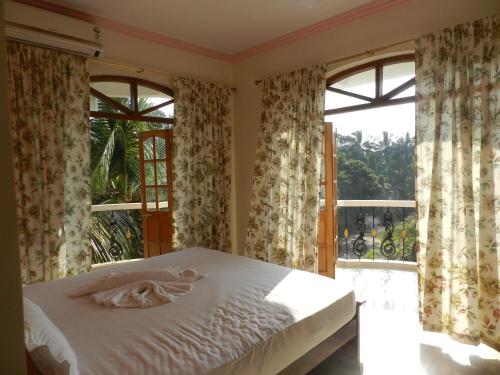 a bedroom with a bed and a large window at Bluesea Beach Resort in Candolim