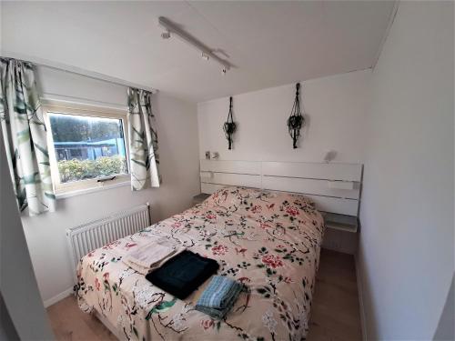 a small bedroom with a bed and a window at Chalet Esdoorn in Putten, Gezellig en Luxe gerenoveerd in Putten
