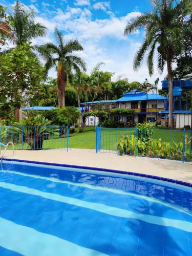 a pool in front of a house with palm trees at Finca Hotel el Edén del Quindío in Calarcá