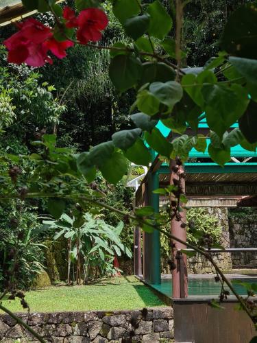 a garden with red flowers and a building at Paraíso Azul Retiro in Abraão