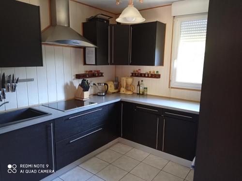 eine Küche mit schwarzen Schränken, einem Waschbecken und einem Fenster in der Unterkunft Chambre privée dans maison au pied de la montagne noire, 5km de Mazamet in Saint-Amans-Valtoret