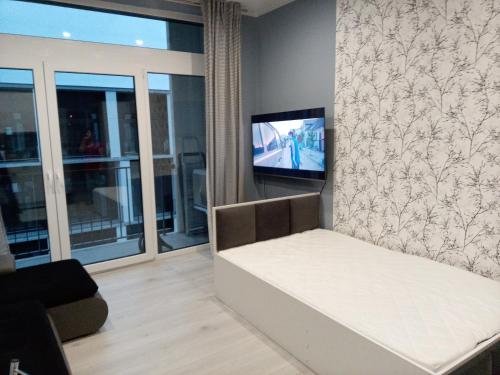 salon z kanapą i telewizorem na ścianie w obiekcie Róża- Lotnisko we Wrocławiu