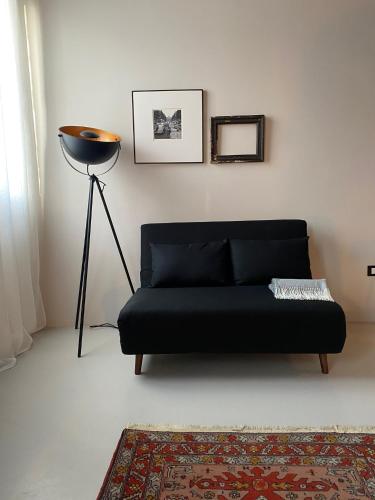 a black couch in a living room with a floor lamp at Casimiro Rooms in Cesena