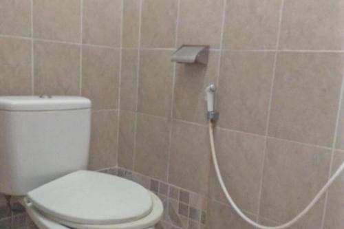 a bathroom with a toilet with a hose attached to the wall at Hotel Olibert Parapat Ajibata Mitra RedDoorz in Parapat