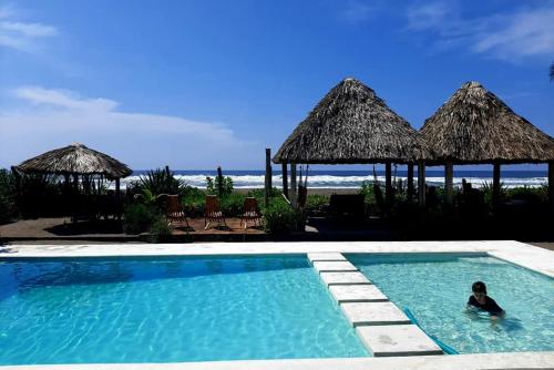 a person in a swimming pool next to a beach at Capricho Beach House in El Zapote