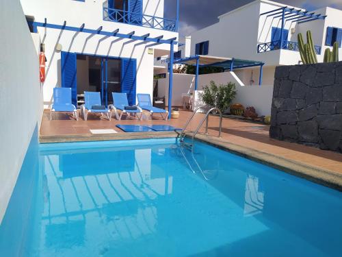 ein Pool mit blauen Stühlen und ein Haus in der Unterkunft Villa la 29 in Playa Blanca