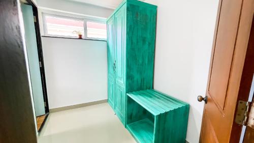 a green cabinet in a room with a window at Calvin's Retreat in Varca