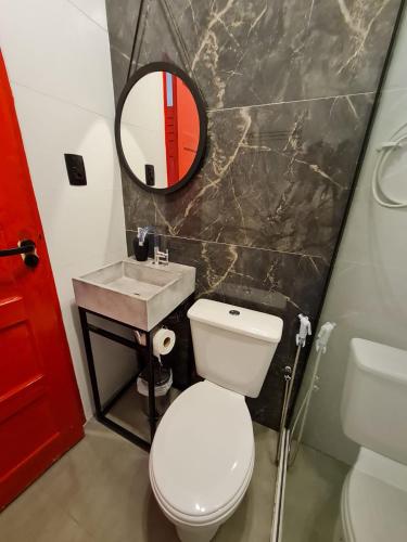 ein Badezimmer mit Toilette, Waschbecken und Spiegel in der Unterkunft GUARALOFT TOKYO Centro de Guarapari in Guarapari