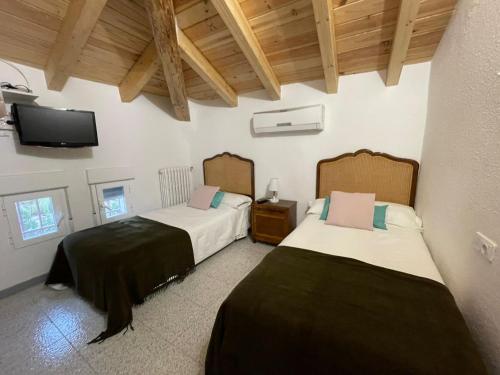 two beds in a room with a tv on the wall at Villa Pachita in Alhama de Aragón