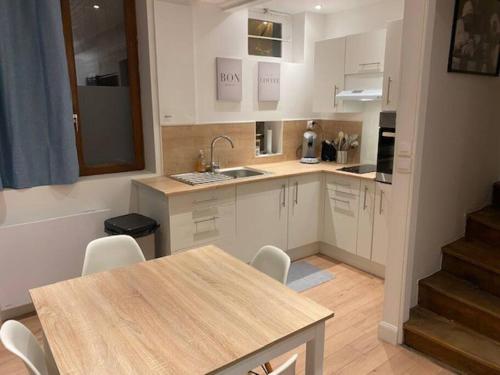 une cuisine avec des armoires blanches et une table et des chaises dans l'établissement Au Petit Bragard- triplex proche centre ville, à Saint-Dizier