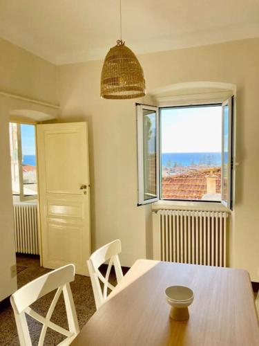 ein Esszimmer mit einem Tisch, Stühlen und einem Fenster in der Unterkunft Casa Paz, centro storico vista mare in Bordighera