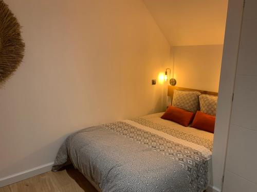 a small bedroom with a bed with orange pillows at Le studio d’Ambre in Chalon-sur-Saône