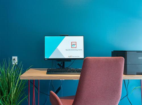 an office desk with a computer monitor and a chair at avid hotel Summerville by IHG in Summerville