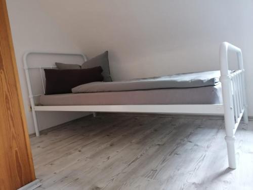 a white bed in a room with a wooden floor at Monteurzimmer Apartment Katlenburg-Lindau FairWohnen24 All-Inkl 24h Check-In in Katlenburg-Lindau