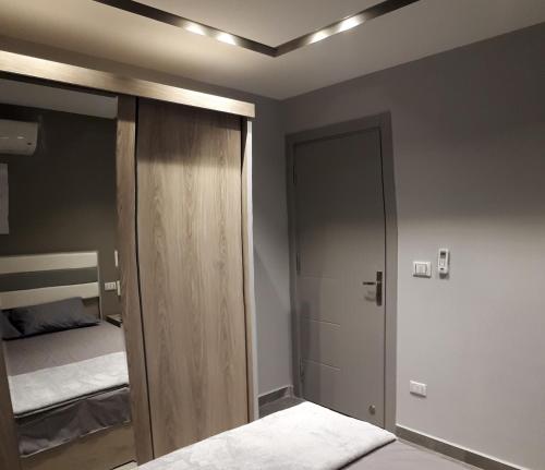 1 dormitorio con armario y puerta con cama en Madinaty 2, en Madīnat ash Shurūq